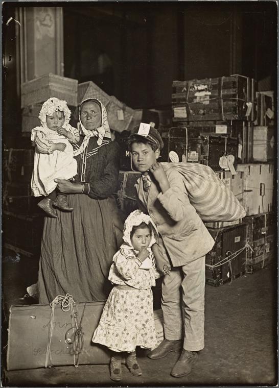 Mother with son and two young daughters in front of pile of luggage