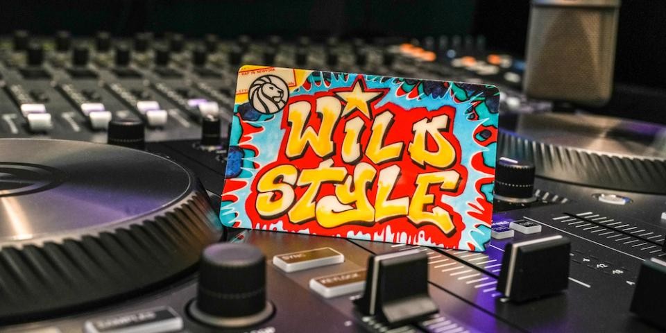 Colorful "Wild Style" hip-hop library card displayed on a black turntable with levers and knobs.