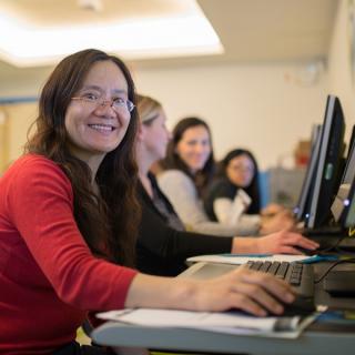 A library patron smiles toward camera while using a computer