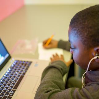 A boy sitting in front of a laptop
