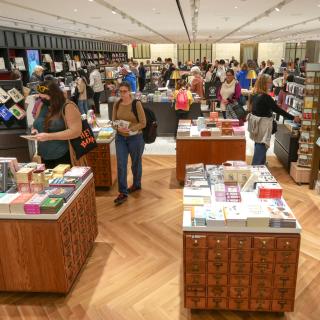 Interior photo of the new NYPL Shop, featuring shoppers looking at various shelves filled with merchandise. 